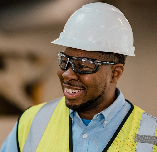 Rainbow Restoration smiling professional wearing hard hat, goggles and yellow vest.