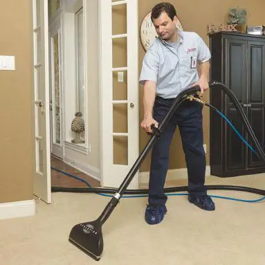 Rainbow technician cleaning floor with vacuum cleaner.