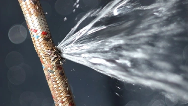 Damaged plumbing hose with water spurting out.