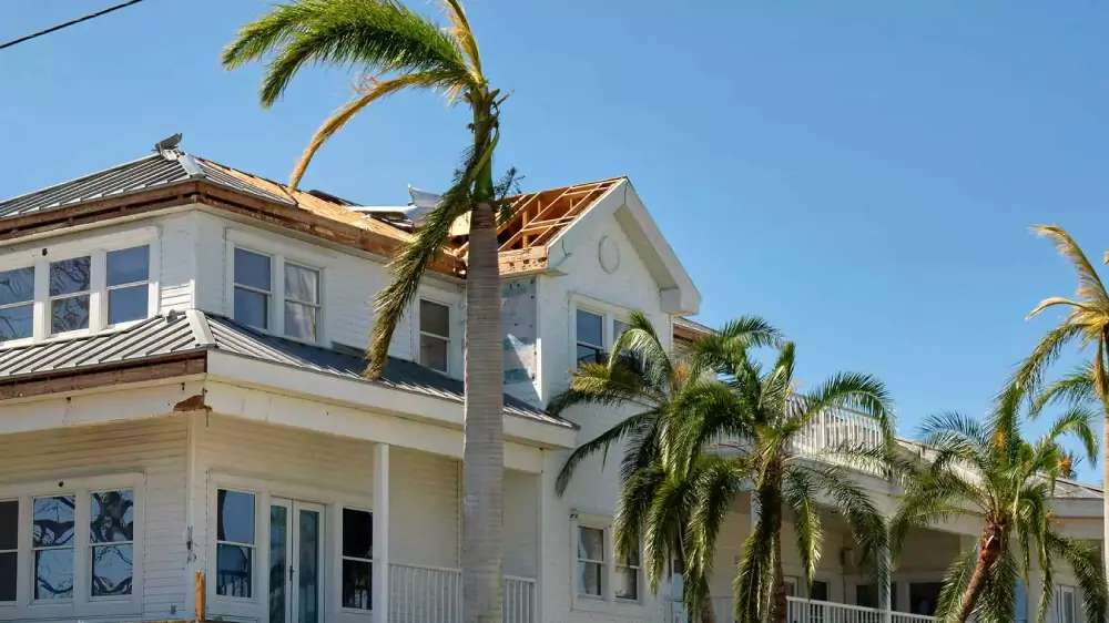 A house with roof and siding damage due to a hurricane.