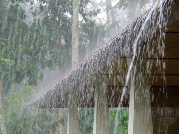 Heavy rain pouring off a residential roof during a storm, illustrating how excess water can lead to potential property damage in Jonesborough homes.
