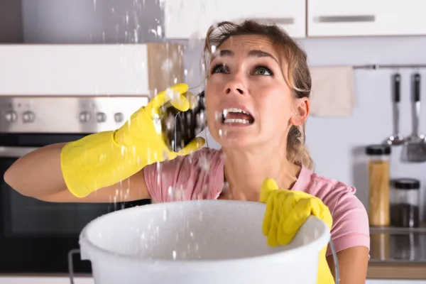 A woman with a yellow rubber glove holds a bucket.