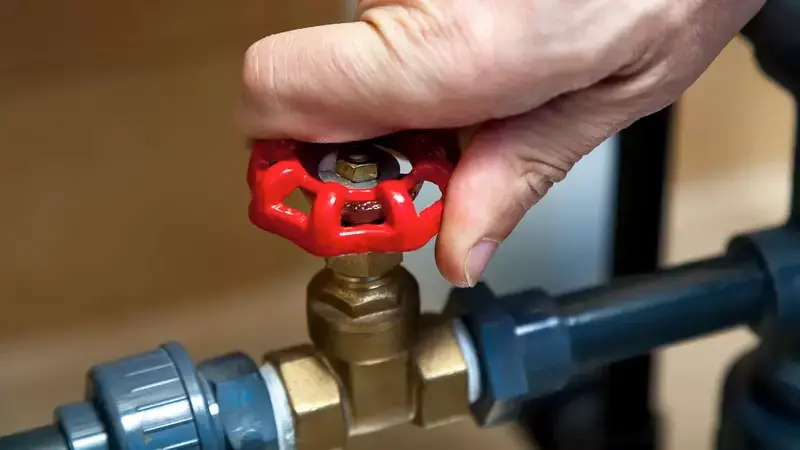 Hand turns off main water shut-off valve.