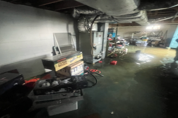 Flooded basement in Kingsport with standing water covering the floor, damaged boxes, and exposed HVAC system, showing the dangers of flood damage cleanup.