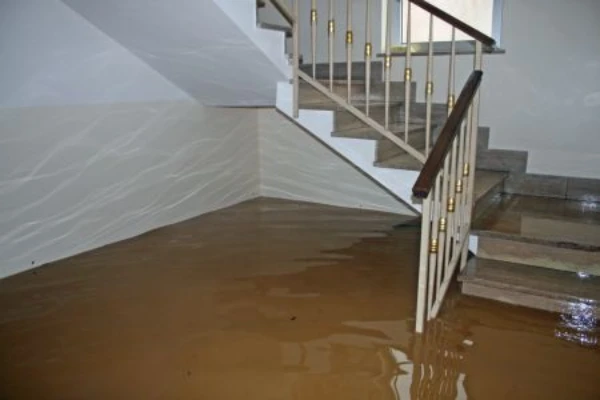 Flooded interior stairwell with murky brown water covering the lower level, indicating severe water intrusion and flood damage inside a residential or commercial building.