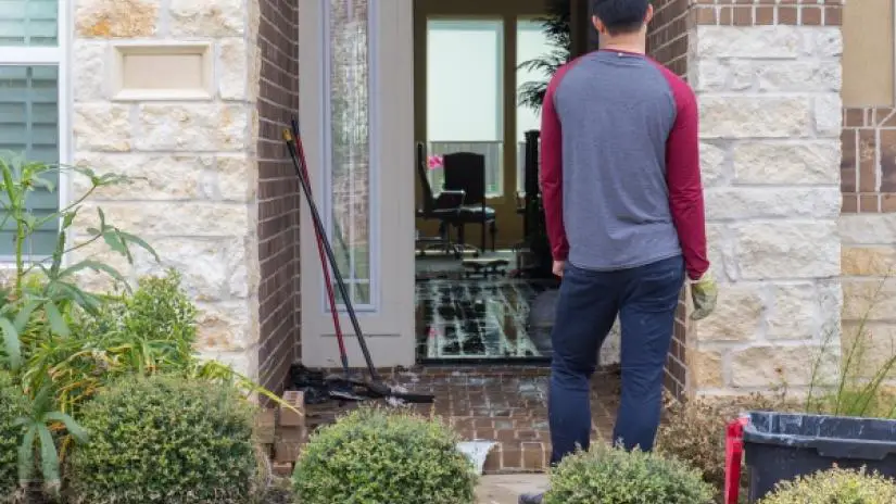 Man standing in front of an open doorway looking into flooded home