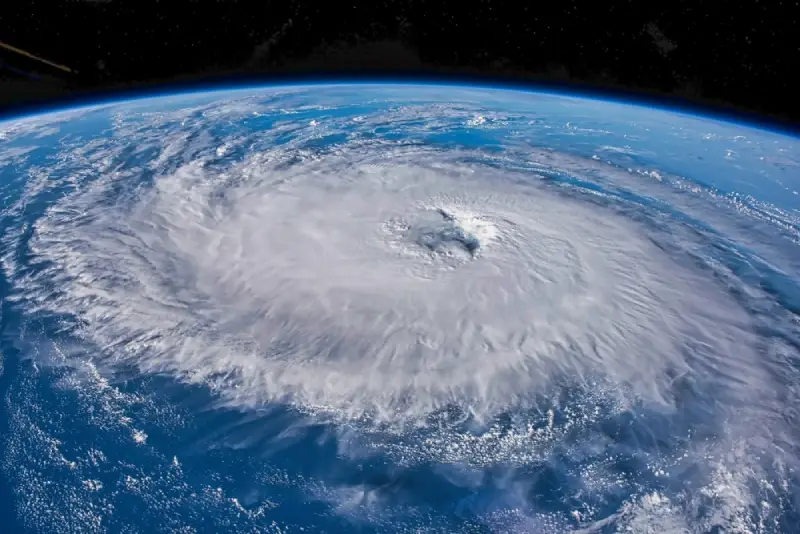 A hurricane over an ocean, seen from space with earth’s horizon in the background.