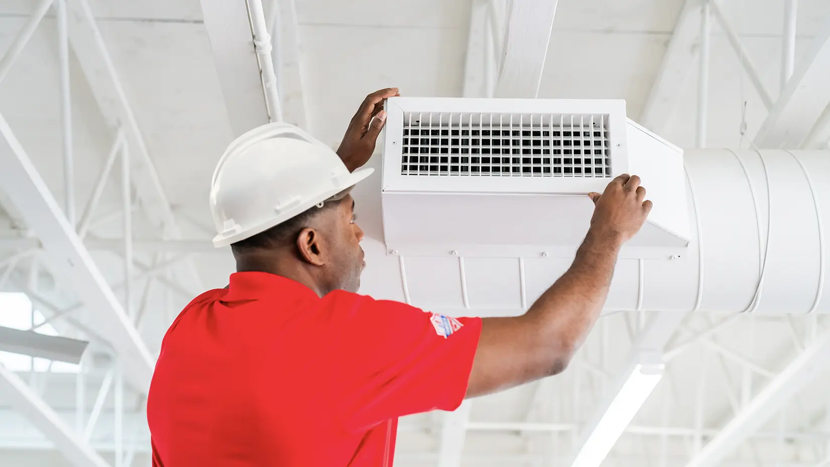 Restoration professional inspecting HVAC vents in the rafters of an industrial building.