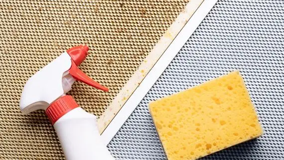 Spray bottle and sponge in greasy kitchen.