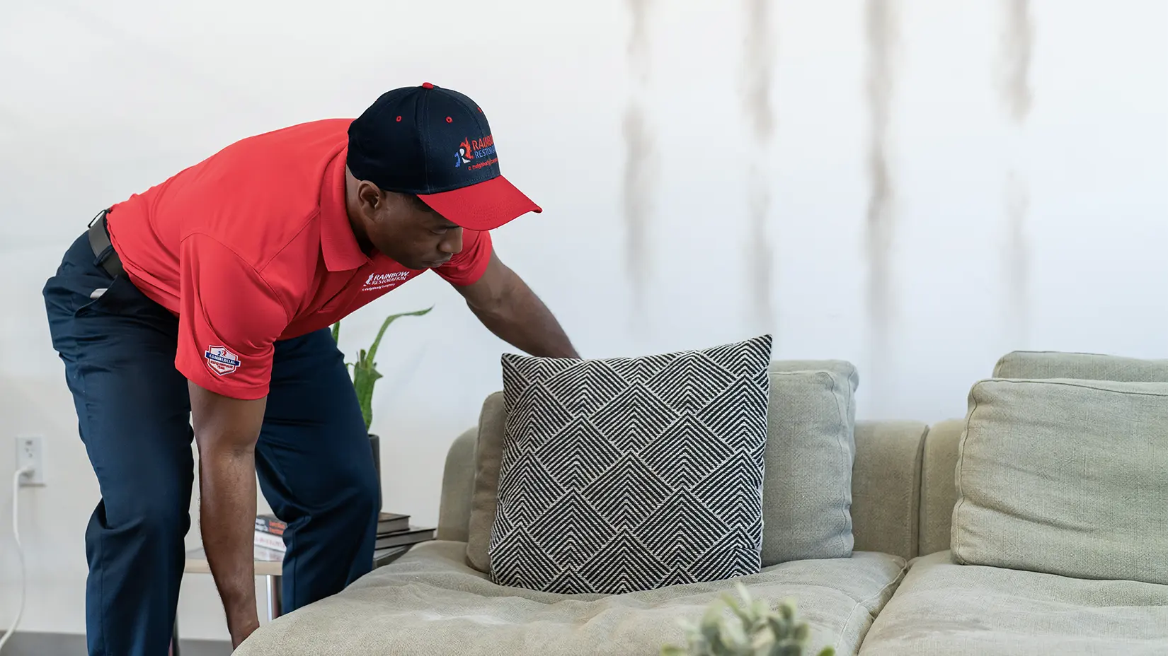 Professional moving couch away from the wall in preparation for cleaning house interior walls.