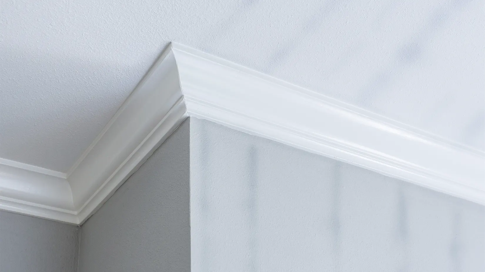 Photograph of a wall, ceiling, and crown molding where ghosting on the walls and ceiling is visible.